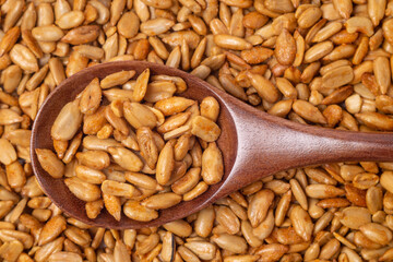 Close-up of peeled sunflower seeds in teriyaki sauce in a wooden spoon, top view
