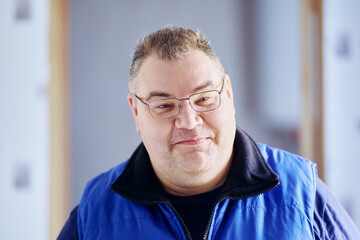 Grinning plump middle aged man of European appearance wearing glasses.