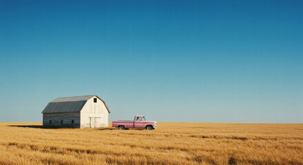 A rustic barn and a pink pickup truck sit amidst golden fields under a clear blue sky.
