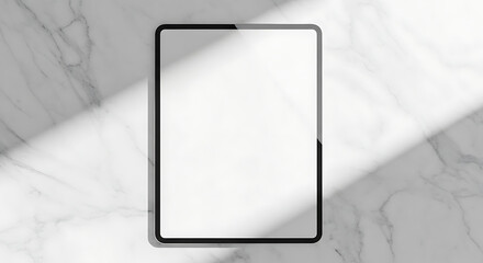 Tablet with blank screen on marble surface, illuminated by a diagonal beam of light.