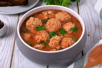 Soup with haddock fish balls in a gray bowl on white table