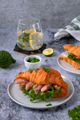 Croissant sandwich with pieces of hot smoked fish catfish clarias on grey table