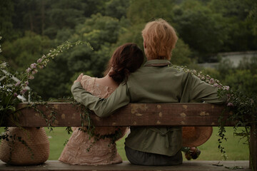 Couple sitting together on a bench surrounded by greenery.