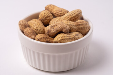 Peanuts in a plate on white background, side view