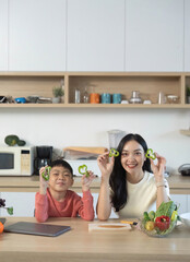 Healthy Fun. Mother and son holding sliced bell peppers in kitchen.