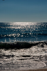 Seascape with beach, waves, sun and empty blue sky
