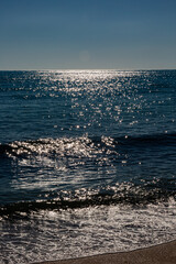 Seascape with beach, waves, sun and empty blue sky