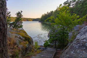 A wooden staircase leads down a rocky coastal slope to the sea in Finland. The eco-friendly setting...