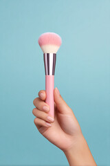 female hand holding pastel makeup brush soft background focus
