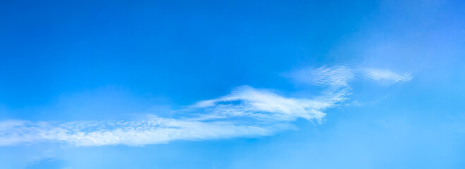 Obraz premium A gentle flight of cascading clouds on the horizon. Bright blue sky with cirrus clouds in high distance, horizontal smoke altitude banner. Weather, spring and summer, peace, hope and purity concept