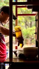 Jakarta, Indonesia, July 25, 2025 : Street vendor preparing mie ayam for customer orders on his...