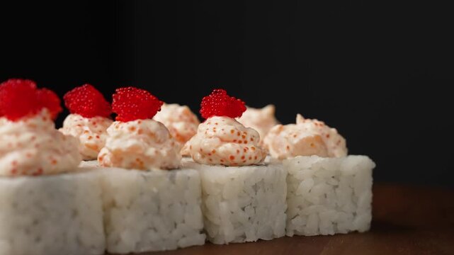 The chef decorates the rolls by adding masago caviar to the rice 