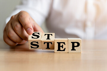 Naklejka premium Hand arranging wooden blocks spelling out the word step