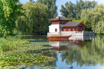 Pavilion with a boat and water lilies. A traditional Chinese pavilion with a wooden boat is located...