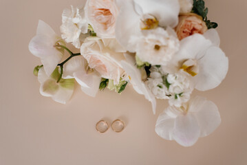 Wedding Rings And White Flowers On Beige Background