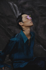 Young man with flower on face in serene environment.