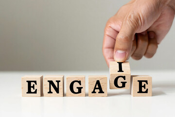 Hand placing the letter i on wooden blocks to spell the word engage