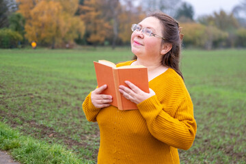 woman with long dark hair holding book, Reader lost in thought, Literary reflection moment,...