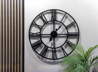 Large Black Round Clock at Wall With Big Roman Numerals Home Decor
