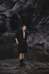 Young man in nature near water and rocks.