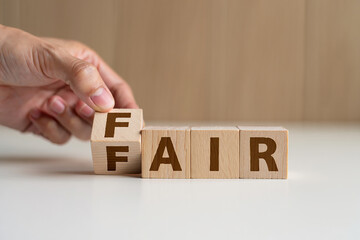 Hand turning wooden blocks to spell the word fair