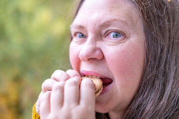 Mature Hungry woman biting sandwich cookies with funny craving expression, comic face expression...