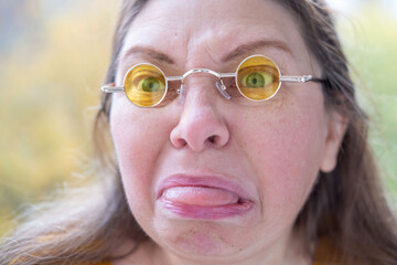Closeup portrait senior woman making silly face sticking out tongue funny expression wrinkles aging...