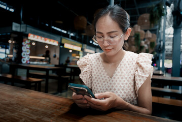 Asian woman using smartphone at the food park in Thailand