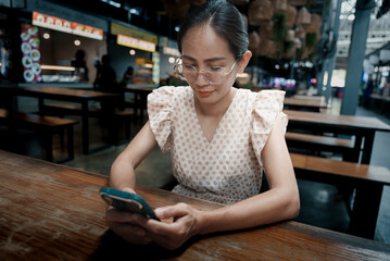 Asian woman using smartphone at the food park in Thailand