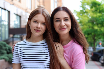 Portrait of beautiful mother and her teenage daughter on city street