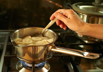 dumplings are boiling in a saucepan in the kitchen