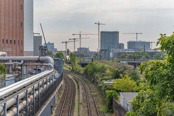 Rail tracks with industrial buildings and numerous construction cranes in the background. Urban...