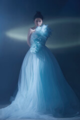 Elegant female model in light blue gown with soft textures.