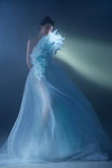 Elegant woman wearing a flowing blue gown with floral accents.