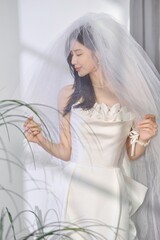 Bride in a white dress with a veil in a bright setting.