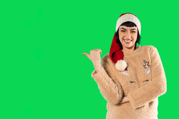 Joyful woman celebrating Christmas wearing a festive sweater and Santa hat against a bright green...