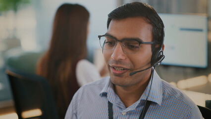 Confident Indian businessman provides customer service and tech support in a diverse corporate...