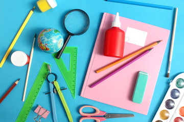 Lots of school supplies lie on a blue background.