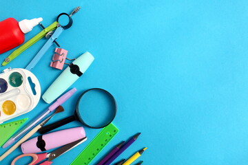 Lots of school supplies lie on a blue background.
