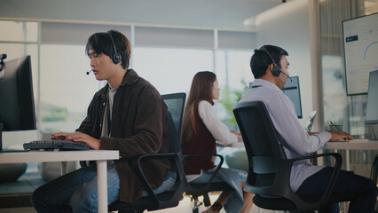 Focused Asian agent at tech support call center provides professional customer service. male...