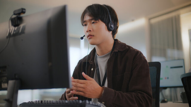Asian business man with headset offers remote tech support, CRM help, and customer service via call center. Diverse office communication with clients, corporate consulting, and telemarketing.