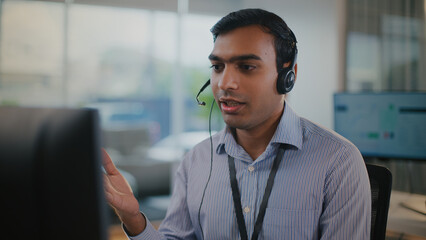 Focused man providing excellent tech support and customer service at call center. He uses headset...