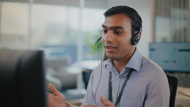 Helpful Indian man at call center offers expert tech support. dedicated customer service representative focused on resolving issues during client call from office center