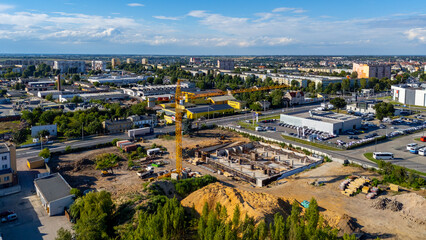 Aerial view of a construction site in Kalisz with a tower crane, excavation works, and modern urban surroundings.