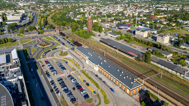 Aerial view of the railway station in Kalisz, Poland, with adjacent roads and a visible water tower in the background cityscape