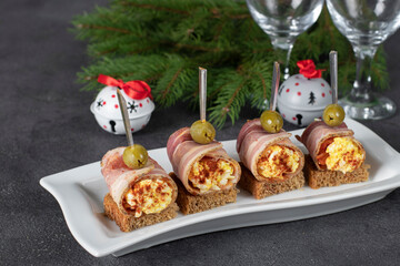 Canape with pancetta rolls with egg and processed cheese on bread toasts