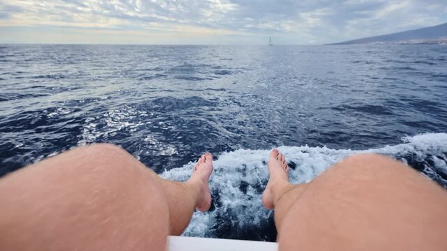 Low angle POV of man&rsquo;s legs as yacht moves steadily across open Atlantic waters