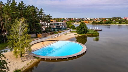 Fototapeta premium unique swimming pool built into Lake Słupeckie in Słupca, surrounded by forest, beach, and modern facilities. Combination of natural lake and recreational area.