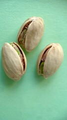 Three pistachios in shells on a light green background