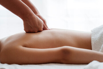 Hands of physio therapist massaging back of teenage girl in health spa
